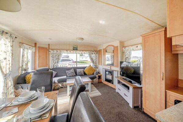 L’intérieur d’une caravane, avec un canapé, une table à manger, un téléviseur et des placards.