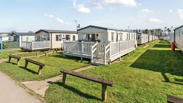 A row of mobile homes with white railings, a grassy lawn, and a pathway. - Cayton Bay Caravan for 6, Pet Friendly & Parking (Scarborough)