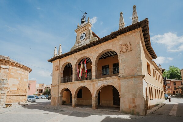 A historic building with a clock tower, arches, and flags.