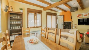 A cozy dining area with wooden furniture, a table with a placemat, and a bookshelf with glassware. - Las Eras III Rural House in Medieval Ayllón – 4 Bedrooms with Bathrooms and Mountain Views (Ayllón)