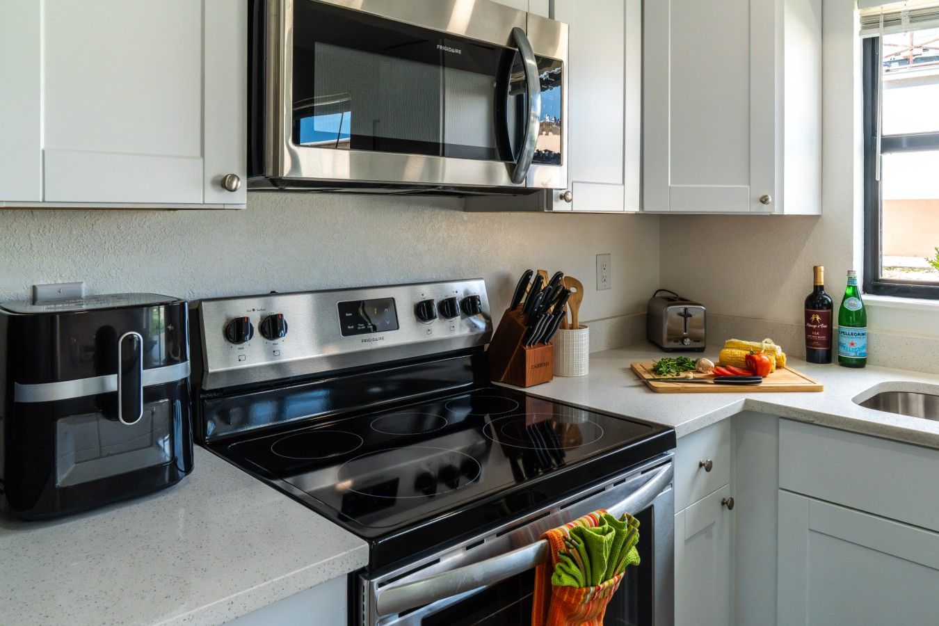 Una cocina con estufa, microondas, tostadora y ventana con vistas.