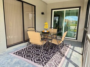 Eine Terrasse mit Tisch und Stühlen, einem gemusterten Teppich und einer Glasschiebetür, die in einen Garten führt.