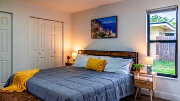 A bedroom with a bed, bedside tables, a window with a view, and a door.