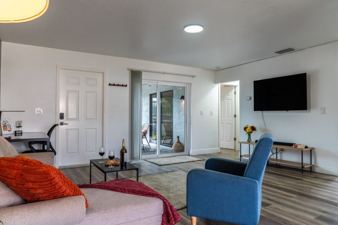 A modern living room with a sofa, a coffee table, a TV, and a sliding glass door leading to a balcony.