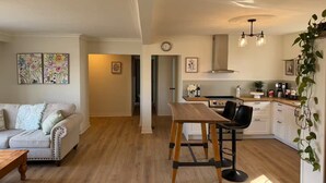 Ein geräumiges Wohnzimmer mit einer Couch, einem Esstisch und einer Küche mit modernen Geräten.