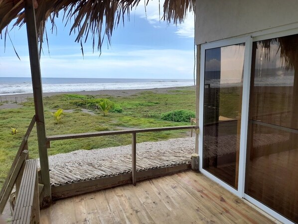 A balcony with a view of the beach and ocean.