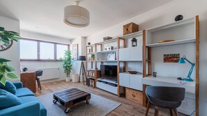 Una sala de estar moderna con un sofá, una mesa de centro, un televisor, un escritorio y estanterías.
