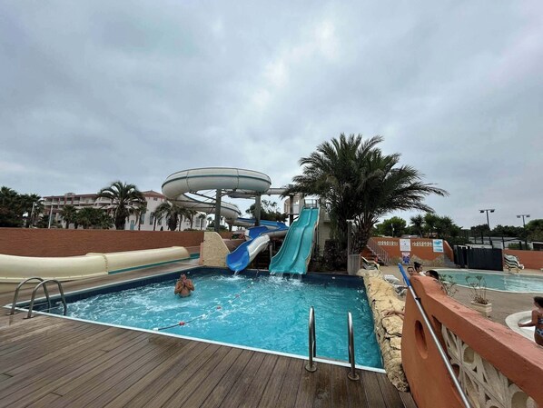 Uma área de piscina com vários toboáguas e um deck de madeira.