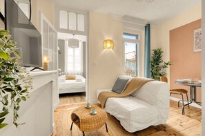 A modern room with a bed, a sofa, a small table, and a wall-mounted light fixture. - Tierra Andina - En centre-ville (Toulouse)