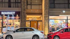 Un edificio con una vetrina che reca la scritta 'San Martin Design' e un cartello con la scritta 'Market'. Due auto sono parcheggiate di fronte.