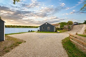 Ein Haus mit Kiesweg, der zu einem Steg an einem See führt, umgeben von viel Grün.