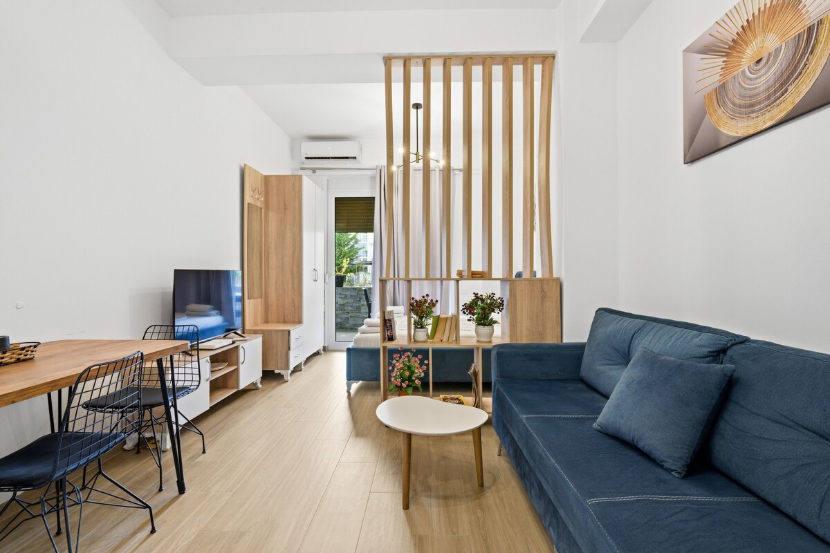 A modern living room with a sofa, TV, dining table, and a decorative partition.