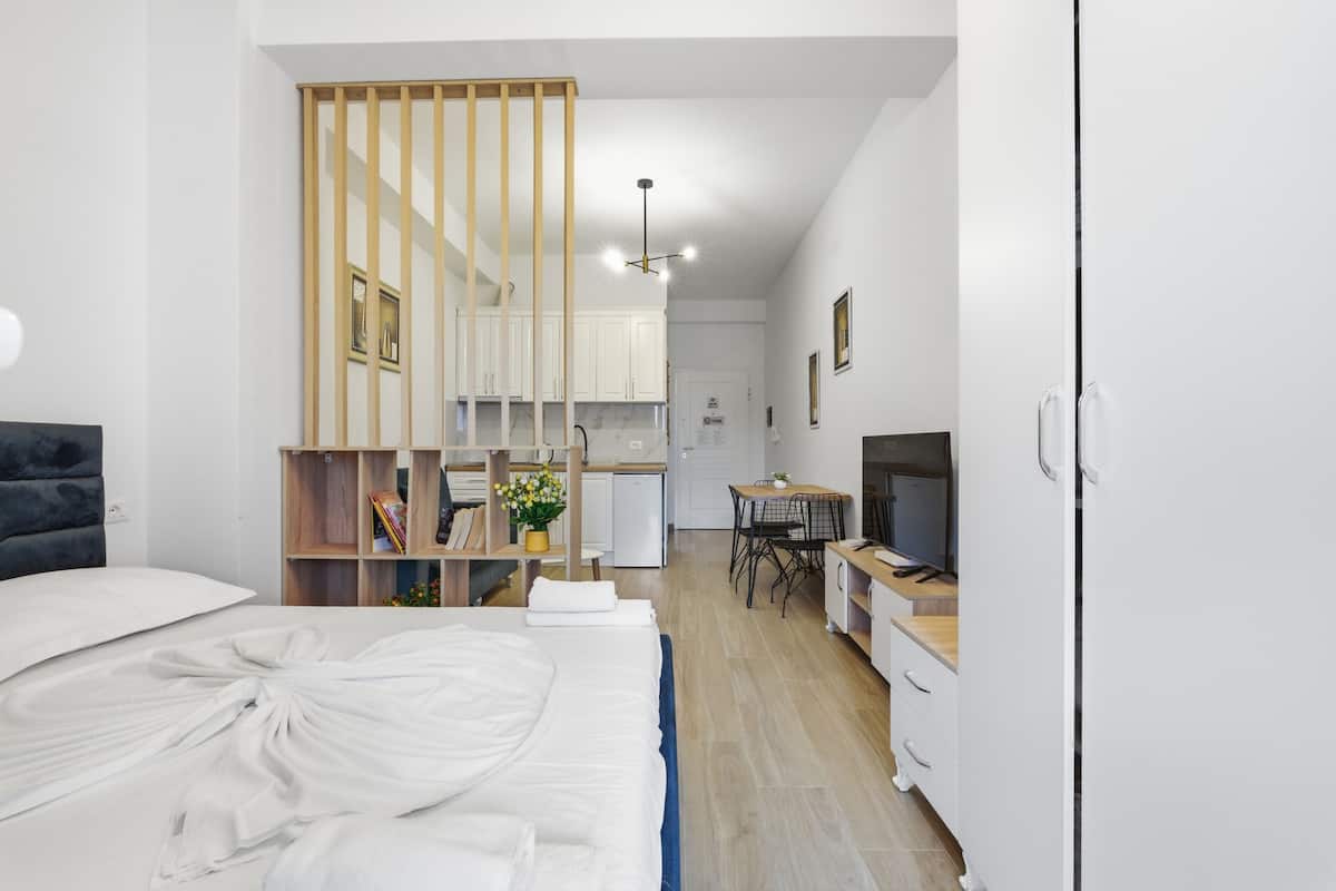 Una habitación de hotel moderna con cama, escritorio, televisor y kitchenette.