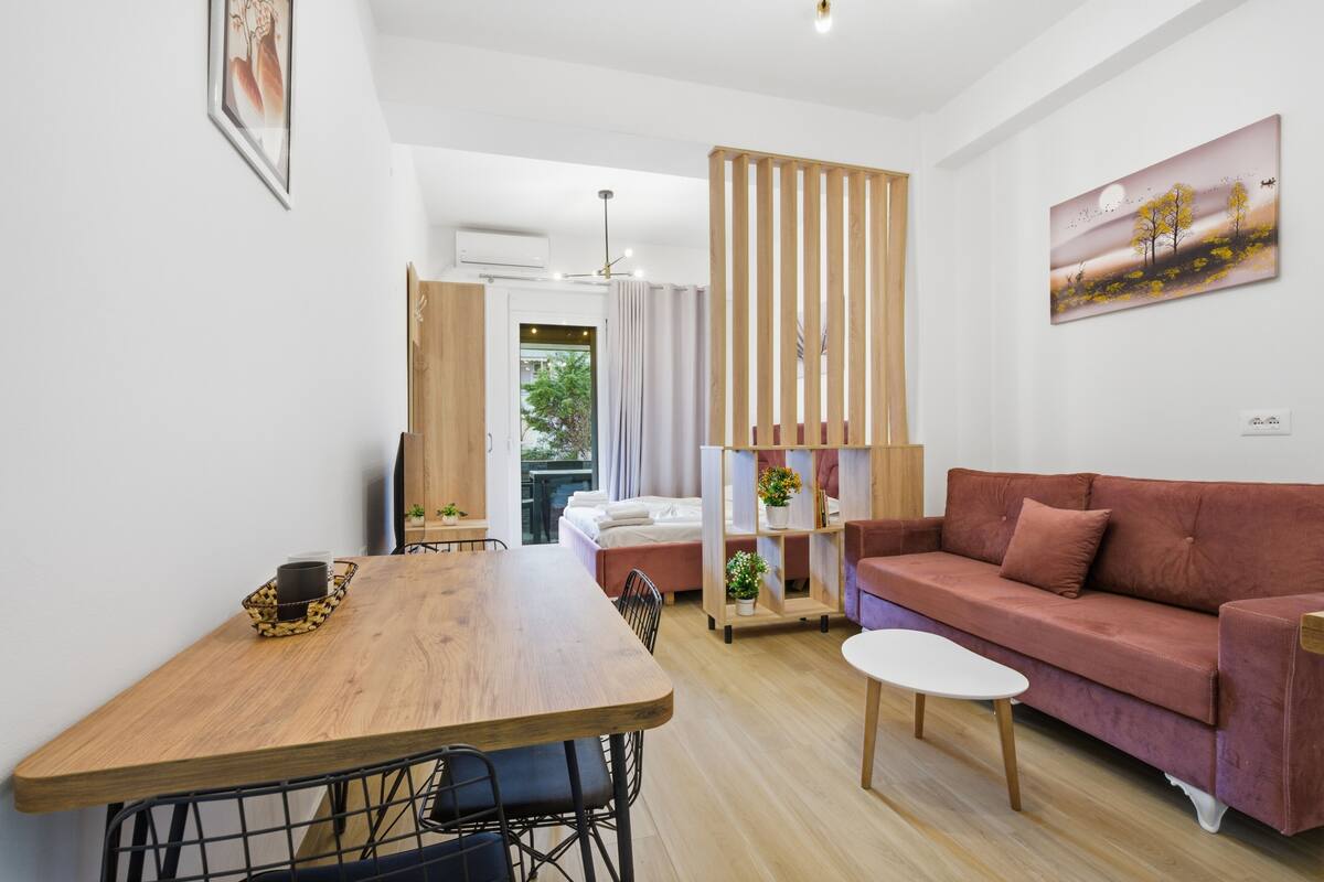 Una sala moderna con una mesa de comedor de madera, un sofá y una mesa de centro blanca.
