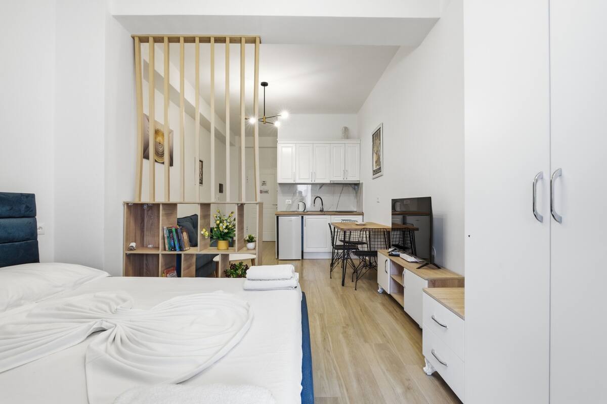 Una habitación de hotel moderna con cama, escritorio, kitchenette y televisor.