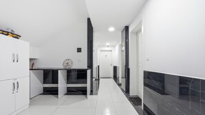 Una cocina moderna con armarios blancos, encimera negra y suelo de baldosas.