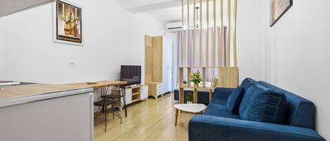 A modern living space with a kitchen, dining area, and a blue sofa.