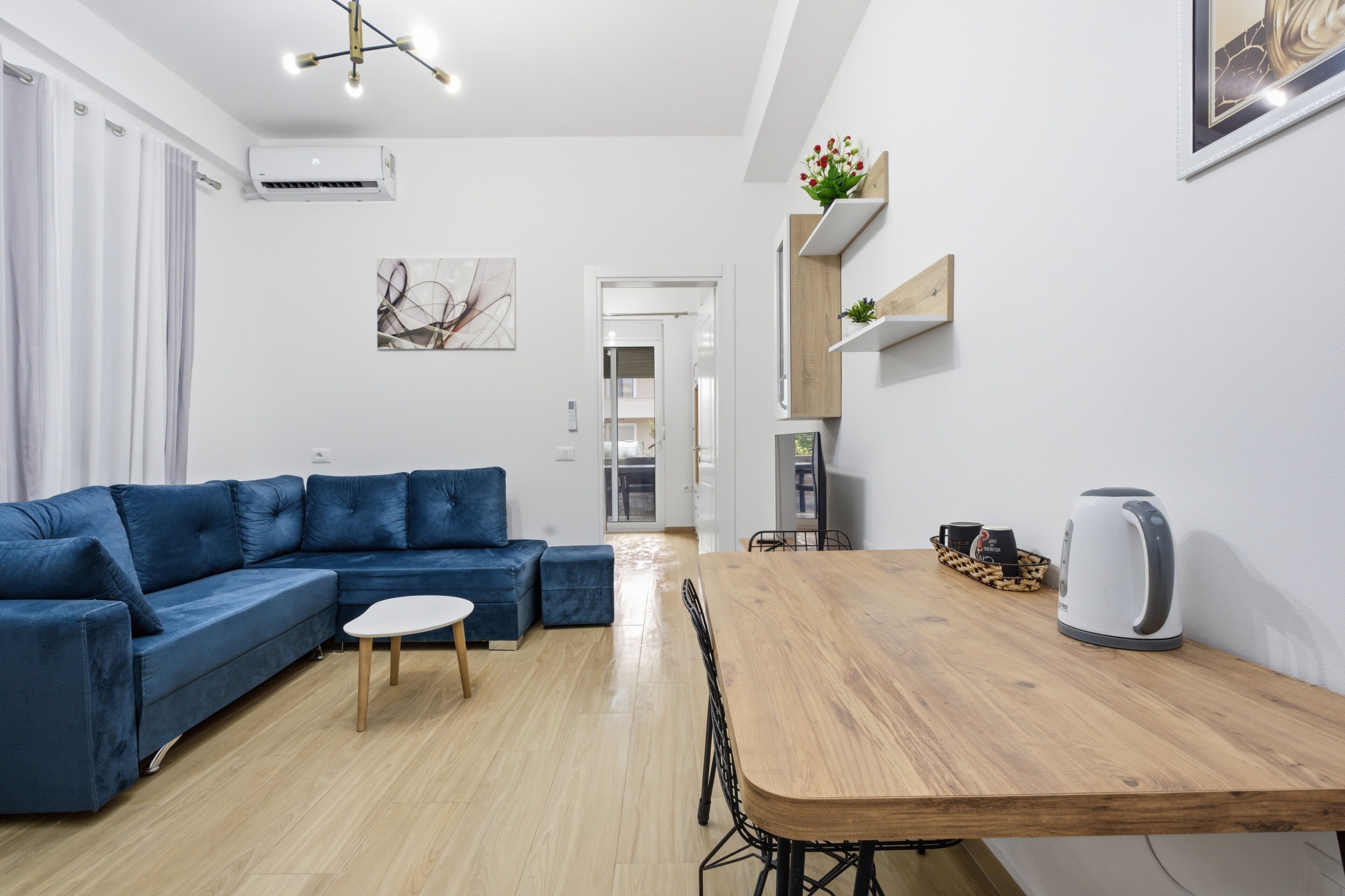Ein modernes Wohnzimmer mit einem blauen Sofa, einem Holzesstisch und einem Wasserkocher.