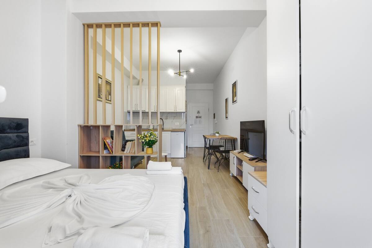 Una habitación de hotel moderna con cama, escritorio, televisor y kitchenette.