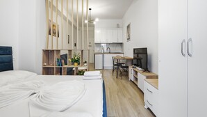 Una habitación de hotel moderna con cama, escritorio, kitchenette y televisor.