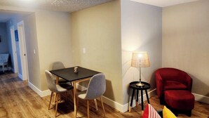 A room with a dining table, chairs, a red armchair, a floor lamp, and a patterned rug. - The Cozy Nook- Adorable 2 Bedroom Home (Columbia Falls)