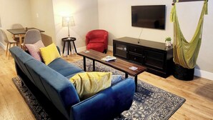 A living room with a sofa, armchair, coffee table, TV, and a hammock. - The Cozy Nook- Adorable 2 Bedroom Home (Columbia Falls)