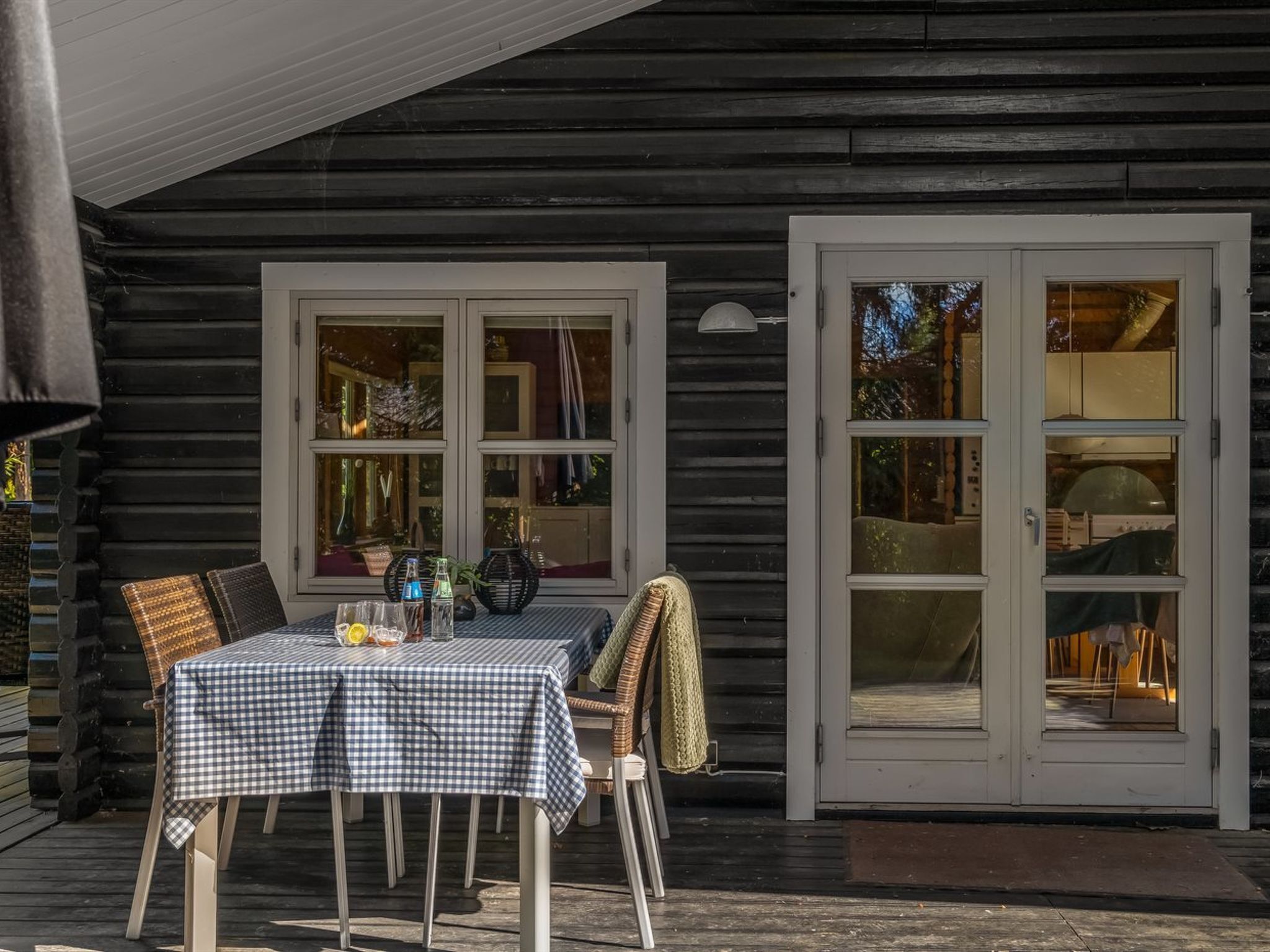 A wooden cabin with a covered porch, a table with chairs, and a sliding glass door.