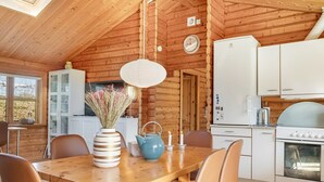 A wooden cabin interior with a dining area, kitchen, and a clock on the wall. - "Tjarko" - 690m to the fjord by Interhome (Storvorde)