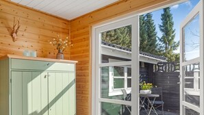 A wooden interior with a green cabinet, a glass door leading outside, and a view of a deck with outdoor furniture. - "Tjarko" - 690m to the fjord by Interhome (Storvorde)