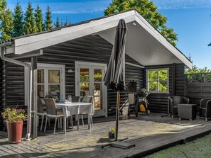A log cabin with a covered patio, outdoor seating, and a view of the surrounding forest. - "Tjarko" - 690m to the fjord by Interhome (Storvorde)