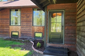 A wooden cabin with a green door, two windows, and a small porch area. - Spacious house near Soldotna, AK (Ridgeway)