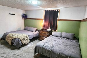 A room with two beds, a dresser, a window with curtains, and a hanging plant. - Spacious house near Soldotna, AK (Ridgeway)
