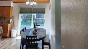 Un comedor con techo de madera, una araña y un ventanal grande.
