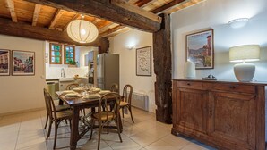 A dining area with a wooden table and chairs, a kitchen in the background, and a rustic wooden beam ceiling. - Domaine Le Pehau 4 - Avec jardin et terrasse (Osserain-Rivareyte)