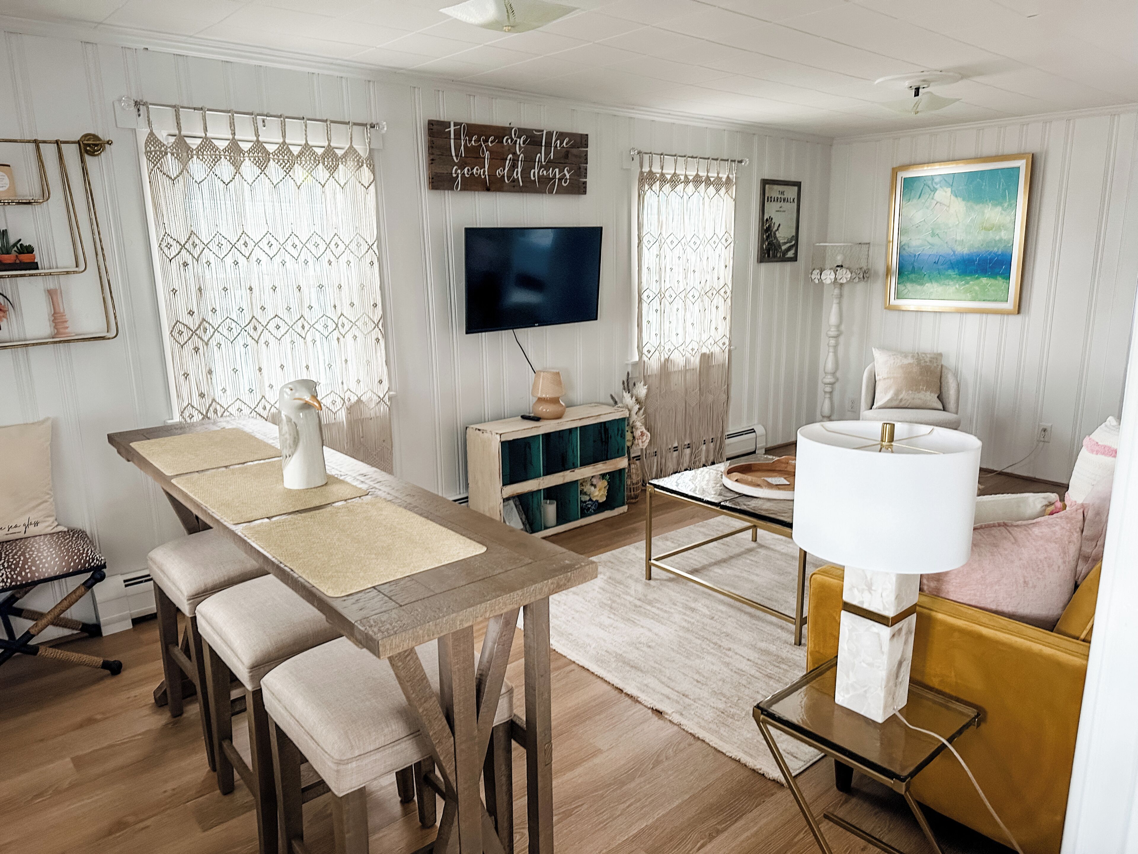 Un salon avec une table en bois, des chaises, un téléviseur, un canapé et une lampe.