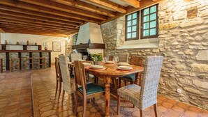 Un coin repas avec une table en bois, des chaises en osier et un mur en pierre.