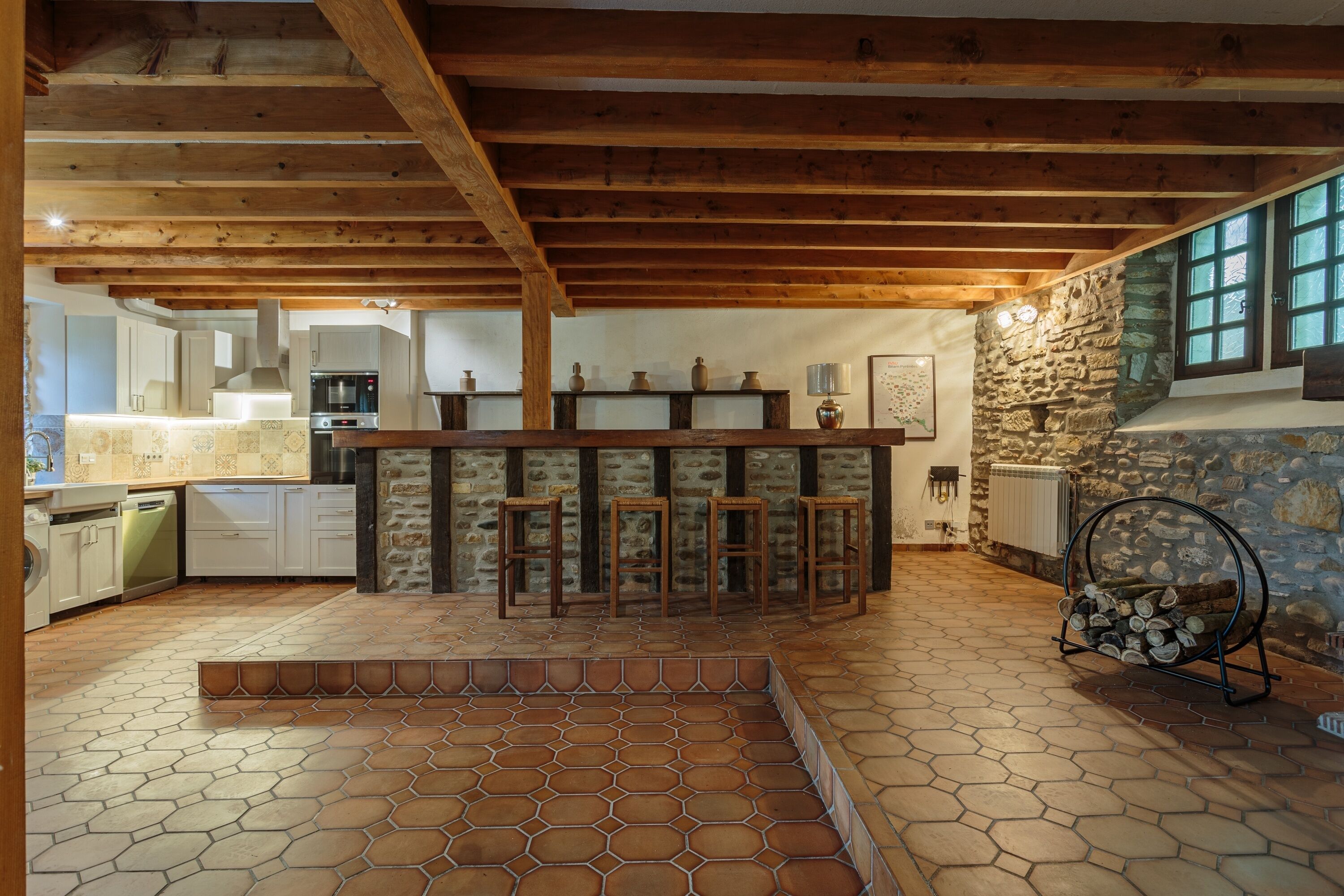 Une cuisine rustique avec des poutres en bois, un mur en pierre et un coin bar.