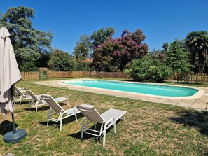 A swimming pool with lounge chairs and a wooden fence in the background. - Domaine Le Pehau 8 - Avec piscine, jardin et terrasse (Osserain-Rivareyte)