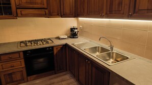 A kitchen with wooden cabinets, a stainless steel sink, a gas stove, and a dishwasher. - Dwelling Euthymia a few minutes from Lake Como (Cosio Valtellino nr. 51)