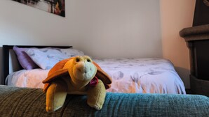 A bed with a white and purple patterned bedspread, a plush toy on a green couch, and a painting on the wall. - Dwelling Euthymia a few minutes from Lake Como (Cosio Valtellino nr. 51)