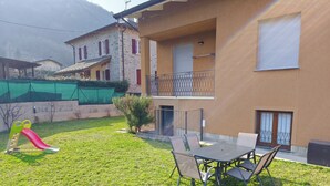 A residential building with a balcony, a slide, and a table with chairs in the yard. - Dwelling Euthymia a few minutes from Lake Como (Cosio Valtellino nr. 51)
