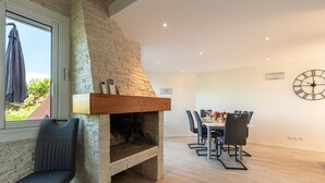 Un comedor moderno con chimenea de piedra, una mesa con sillas y un reloj de pared.