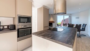 Una cocina moderna con electrodomésticos integrados, una isla grande y una zona de comedor con sillas.