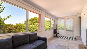 Una sala de estar moderna con un sofá, una mesa de centro y grandes ventanales que ofrecen vistas a zonas verdes.