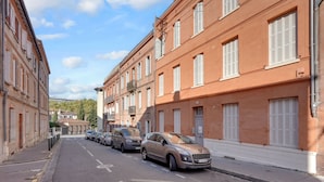 A street lined with buildings, parked cars, and a clear sky. - Prisma - Climatisé, proche gare (Toulouse)