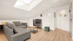 A modern living room with a skylight, grey sofa, wooden coffee table, and a TV. - Prisma - Climatisé, proche gare (Toulouse)