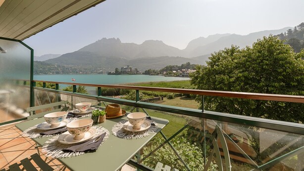 Un balcon avec une table préparée pour le thé, d’où l’on peut admirer un lac et des montagnes.
