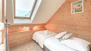 Une chambre avec un plafond en pente, des murs en bois, un puits de lumière, un lit avec une literie blanche et une affiche accrochée au mur.