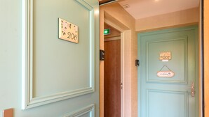 Un couloir d’hôtel avec les portes numérotées 206 et 207, un panneau indiquant la sortie de secours et un interphone.
