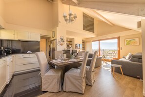 Eine moderne Küche mit weißen Schränken, ein Essbereich mit Tisch für vier Personen und ein Balkon mit Blick.